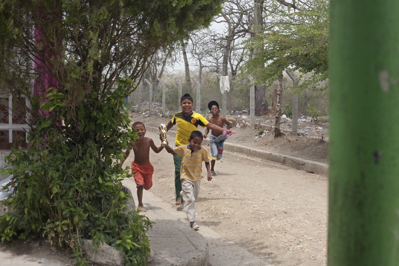 Kids run with a newly minted trophy near Yuris' house in San Jose de los Campanos, a sprawling barrio on the periphery of Cartagena. Although these communities are tight, the incidence of crime remains high because of the very real need for food, shelter, money.&amp;nbsp;